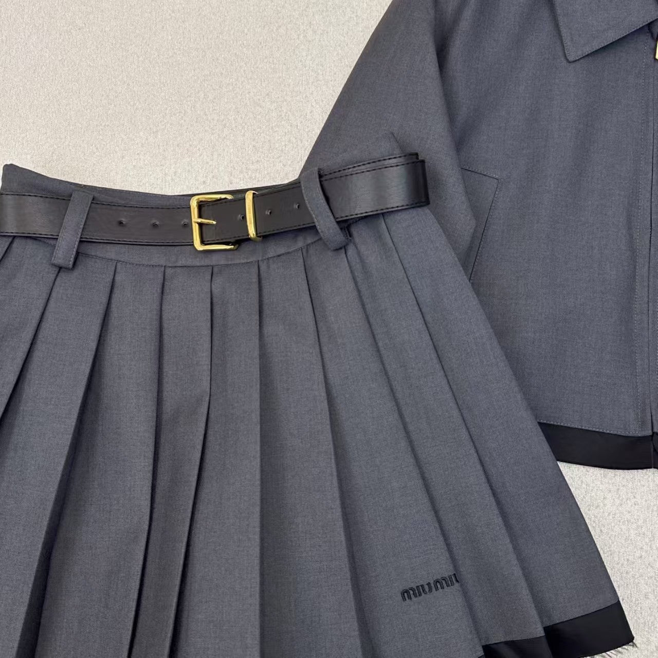 Tailleur veste à revers épissés et jupe plissée ceinturée